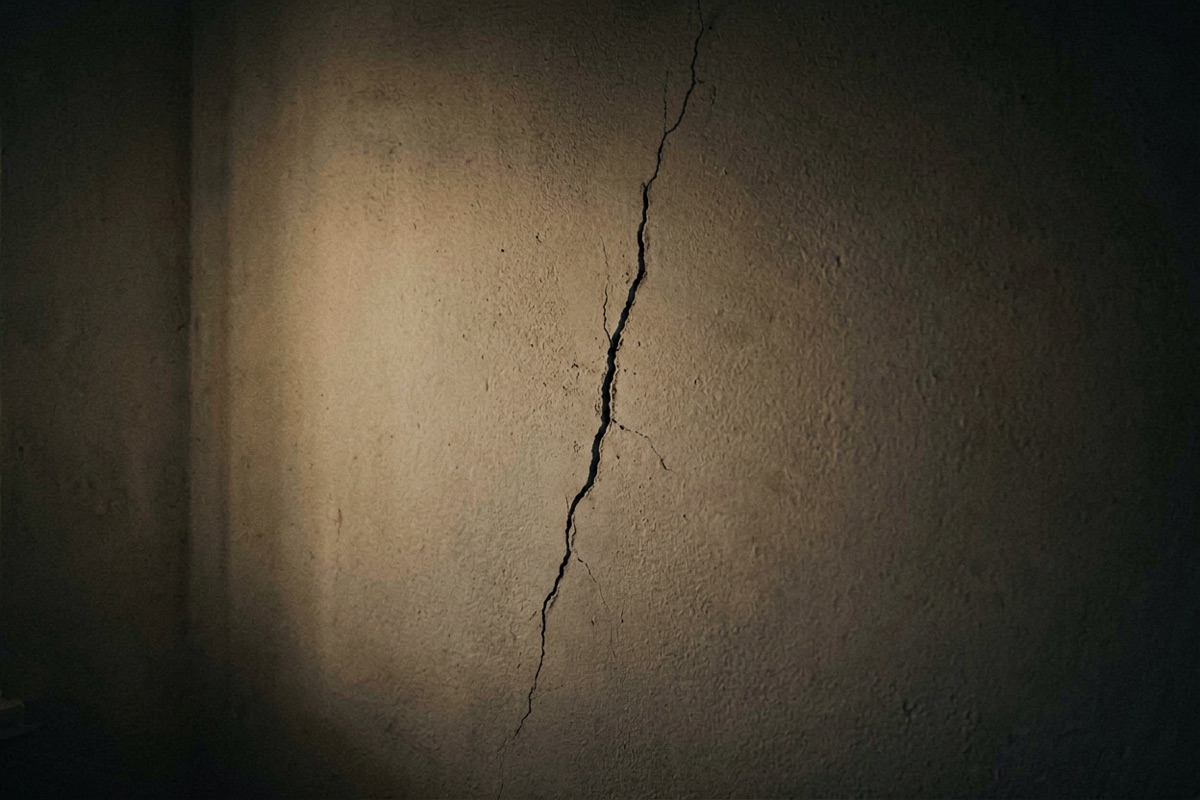 A hairline crack running down an interior wall, tapering to a point (AI-generated illustration)