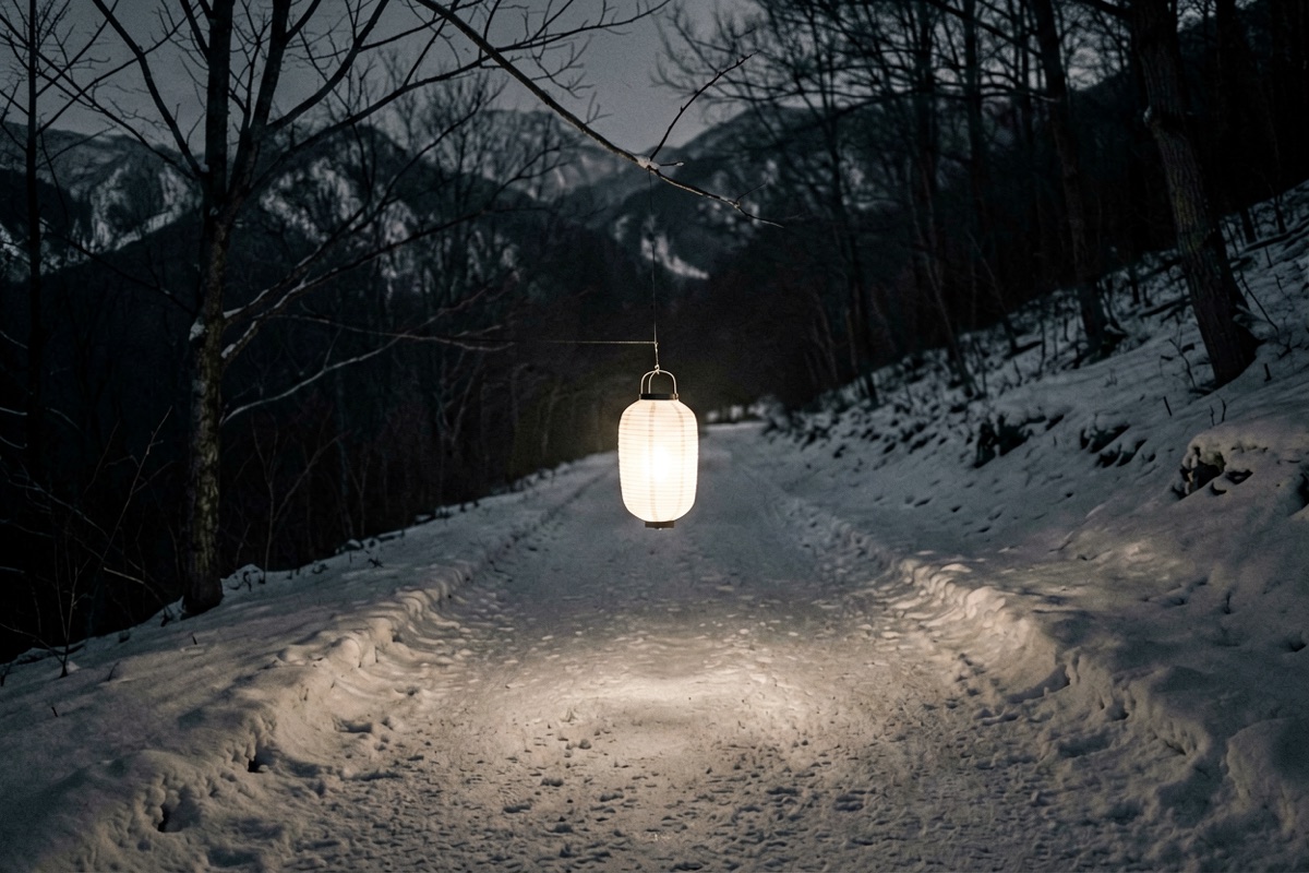 A white paper lantern carried along a snow-covered road at night (AI-generated illustration)